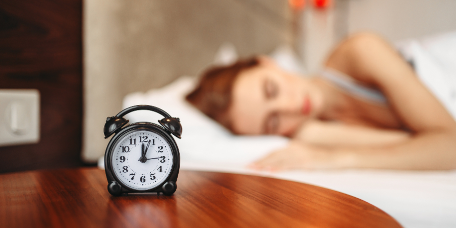 An alarm clock placed in front of a bed